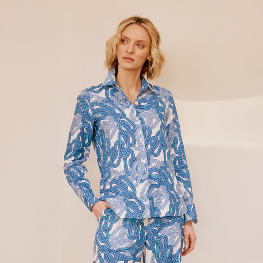 Woman wearing a blue and white patterned shirt and pants on a beige background