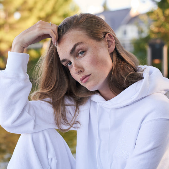 Person wearing a white hoodie outdoors with blurred background