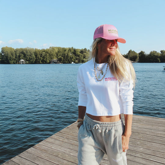 Person wearing a white long-sleeve shirt and pink cap by a lake