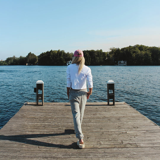 Person walking on a wooden dock by a lake with trees in the background
