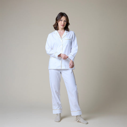 Woman wearing a white pajama set against a plain background