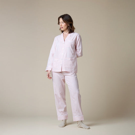Woman wearing a light pink pajama set against a beige background