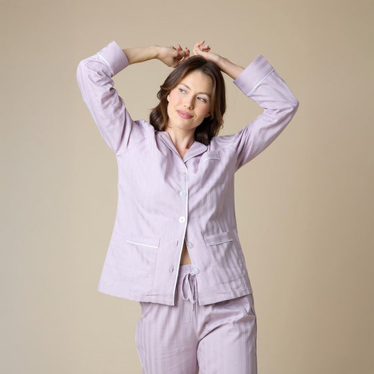 Woman wearing a light purple pajama set against a beige background