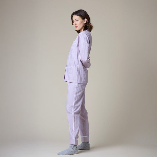 Woman wearing a light purple pajama set against a plain background