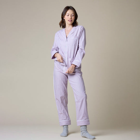 Woman wearing a light purple pajama set against a beige background