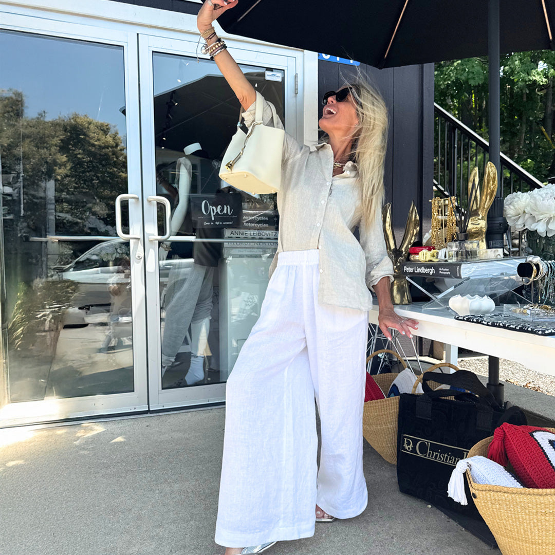 Skye Flowers is in a white outfit standing outside the Muskoka store with various items around her.