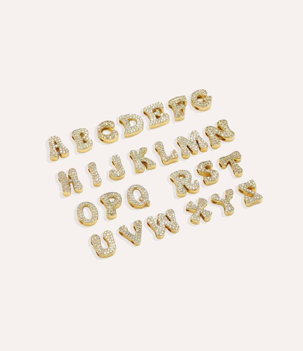 Gold Baby Letter Charms arranged neatly on a white surface, showcasing each initial.