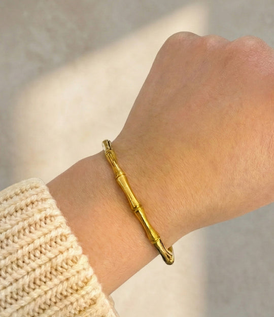 Gold bracelet on a wrist with a neutral background