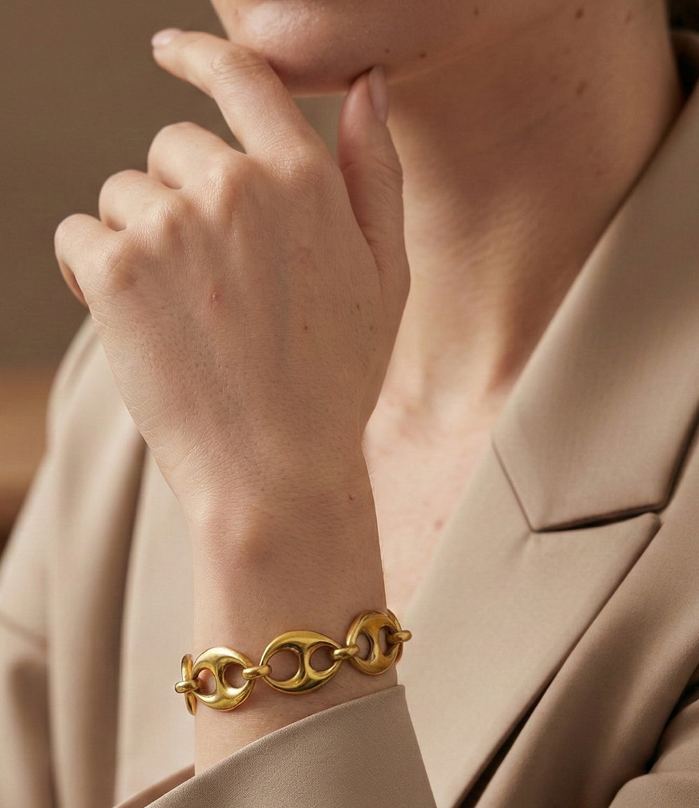 Gold bracelet on a wrist with a neutral background