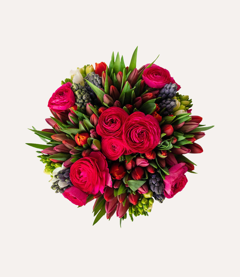 Bouquet of red and pink flowers with green leaves on a light gray background