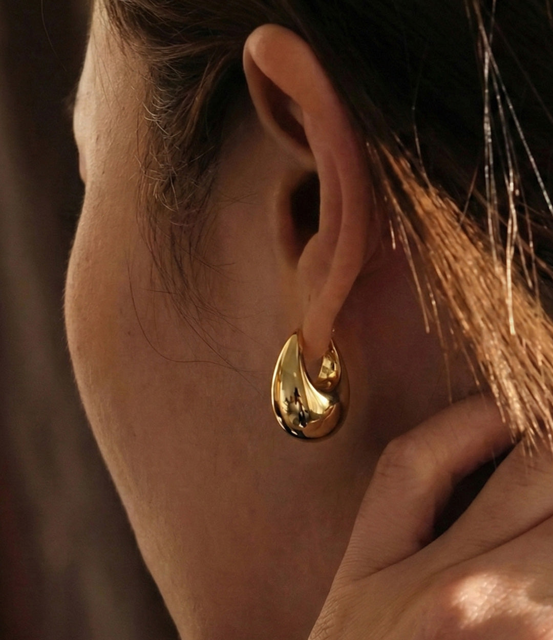 Close up of a model wearing the Bianca Earrings showing the unique modern shape and elegant fit against a neutral background.
