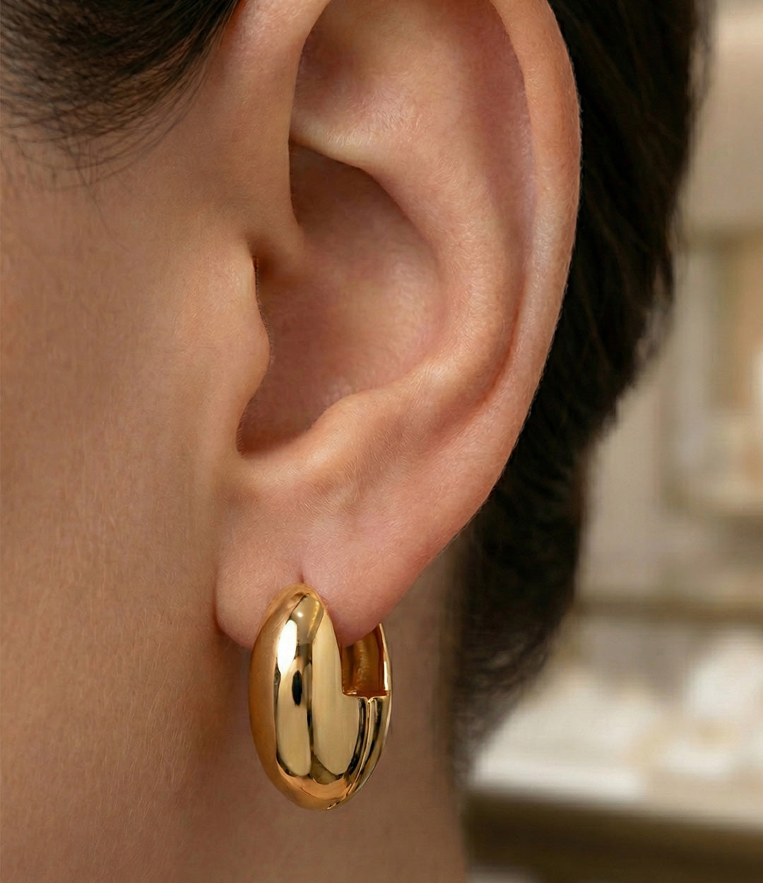 Gold hoop earring worn by a person