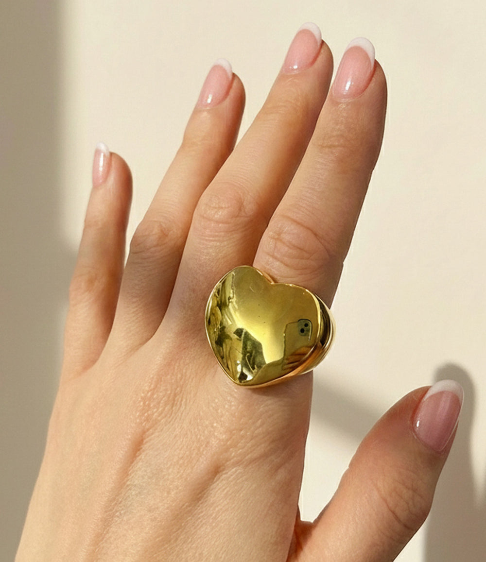 Woman's hand modeling the Big Love Ring on the ring finger, showcasing the bold chunky heart signet design