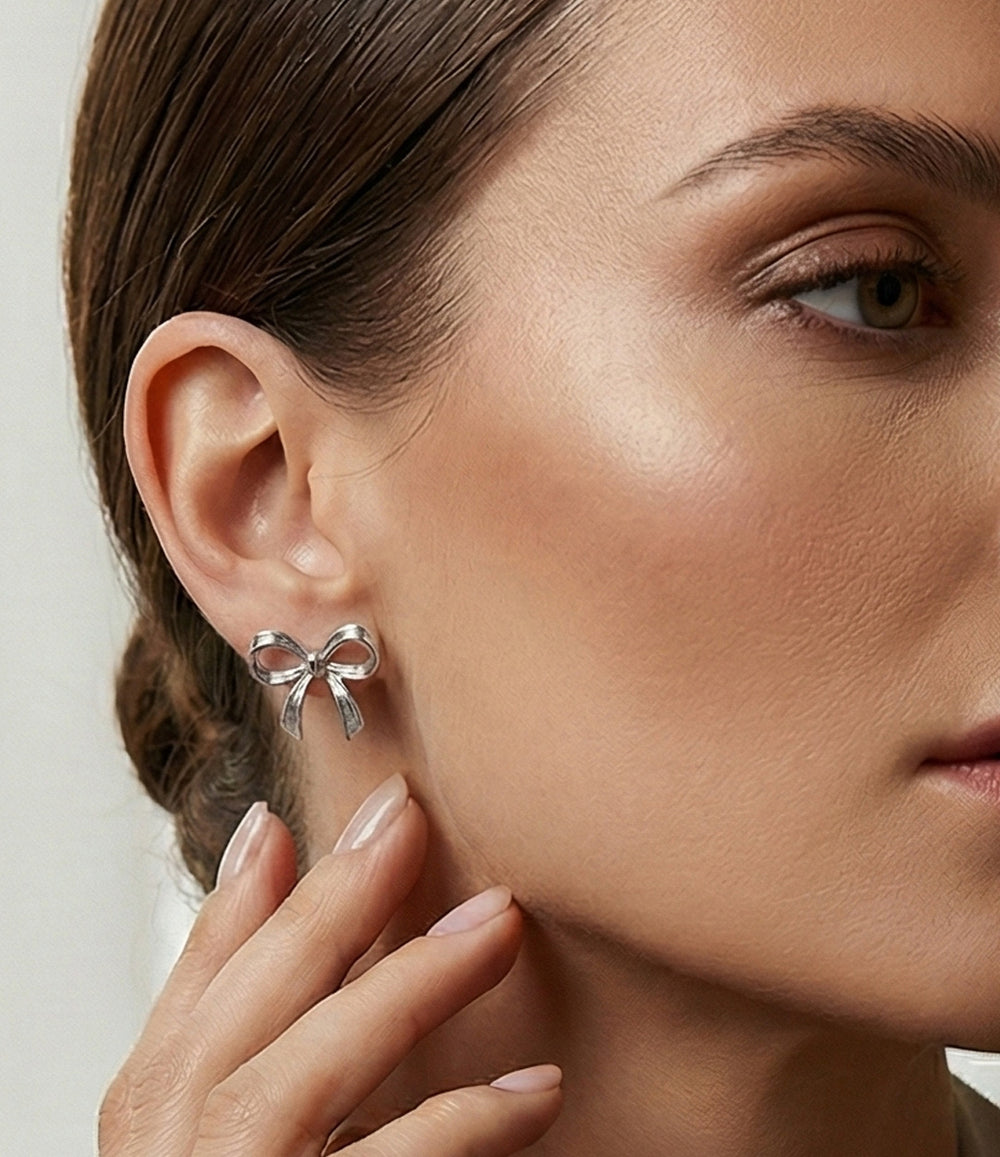 Close-up of a woman wearing a silver bow-shaped earring.