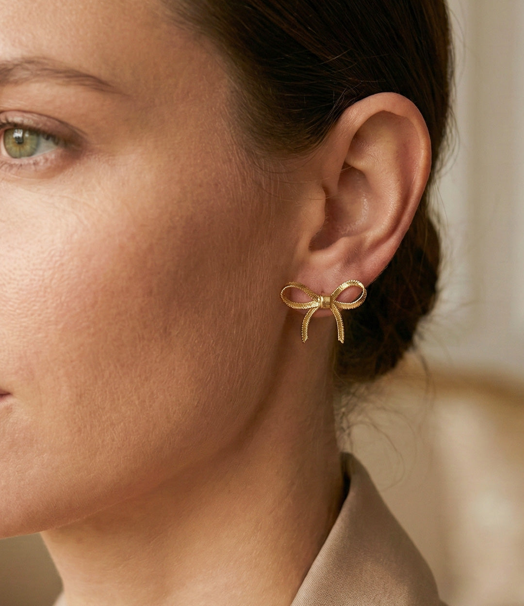 Close-up of a woman wearing a gold bow-shaped earring.