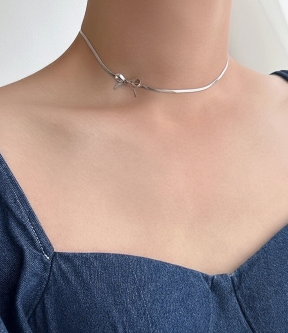 Close-up of water and tarnish proof silver bow pendant necklace