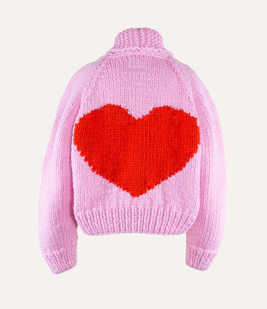 Pink sweater with a red heart design on the back against a light pink background