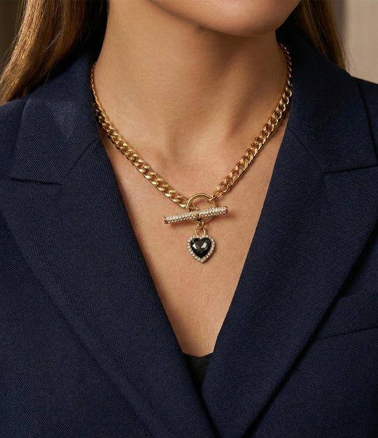 Gold chain necklace with a heart pendant on a person wearing a navy blazer.