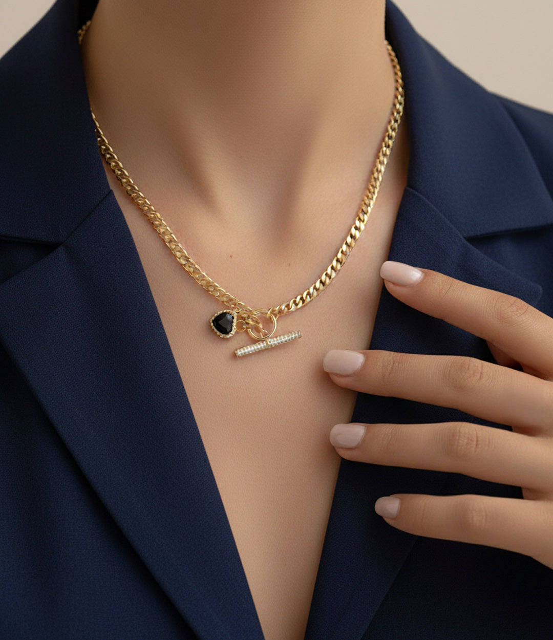 Gold necklace with a heart pendant and tag on a mannequin wearing a navy blazer.