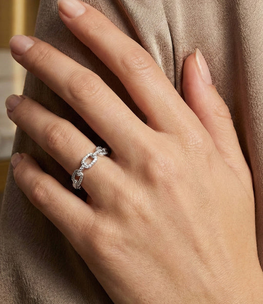 Woman's hand modeling the Chain Link Ring on the ring finger, showcasing the sleek 18k gold plated design and delicate diamond sparkle.