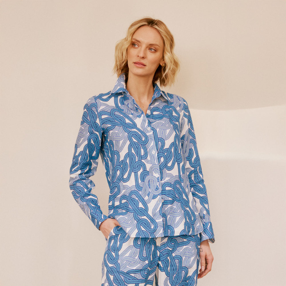 Woman wearing a blue and white patterned shirt and pants on a beige background