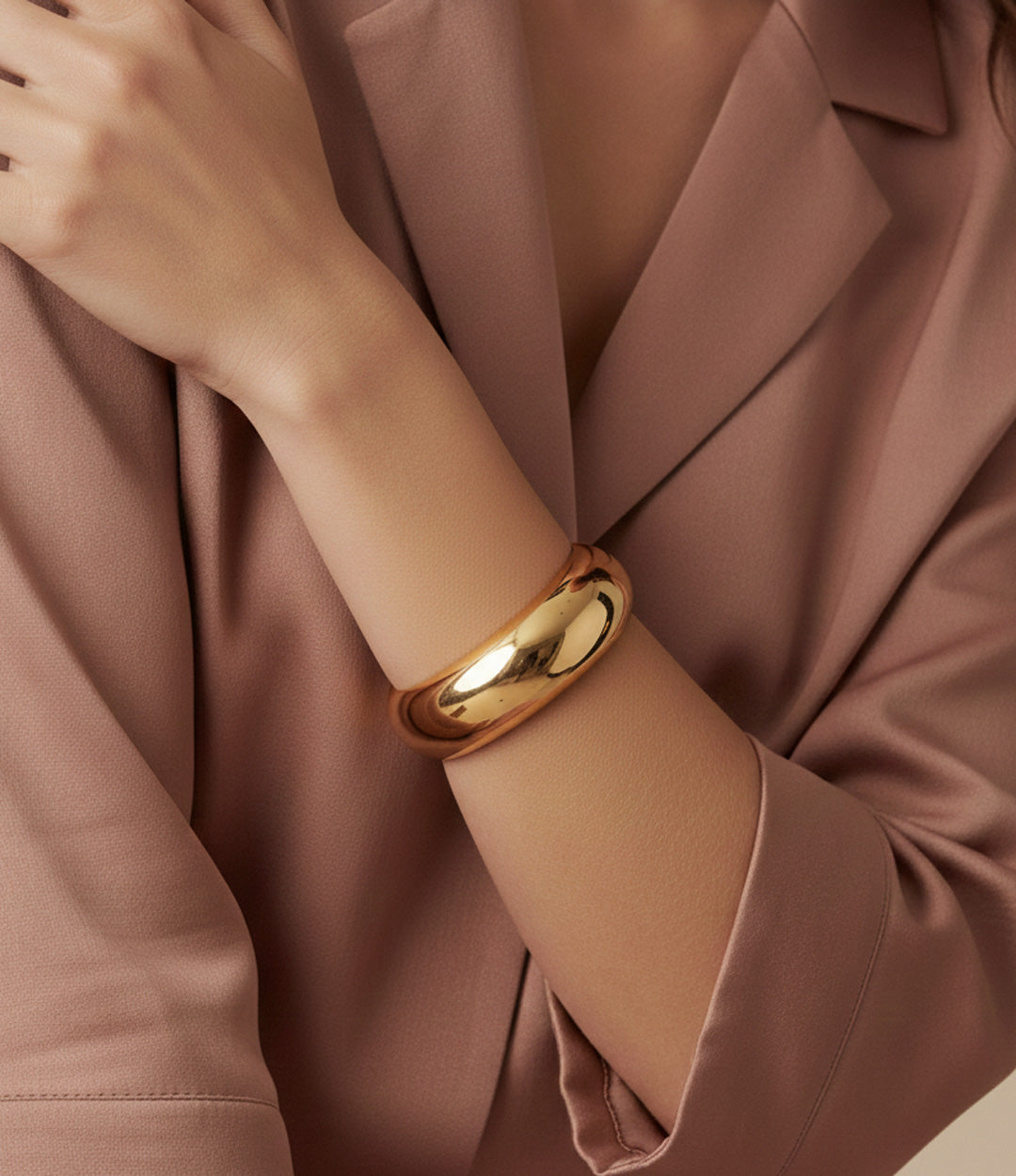 A classic gold bracelet on a person's wrist with a blurred background