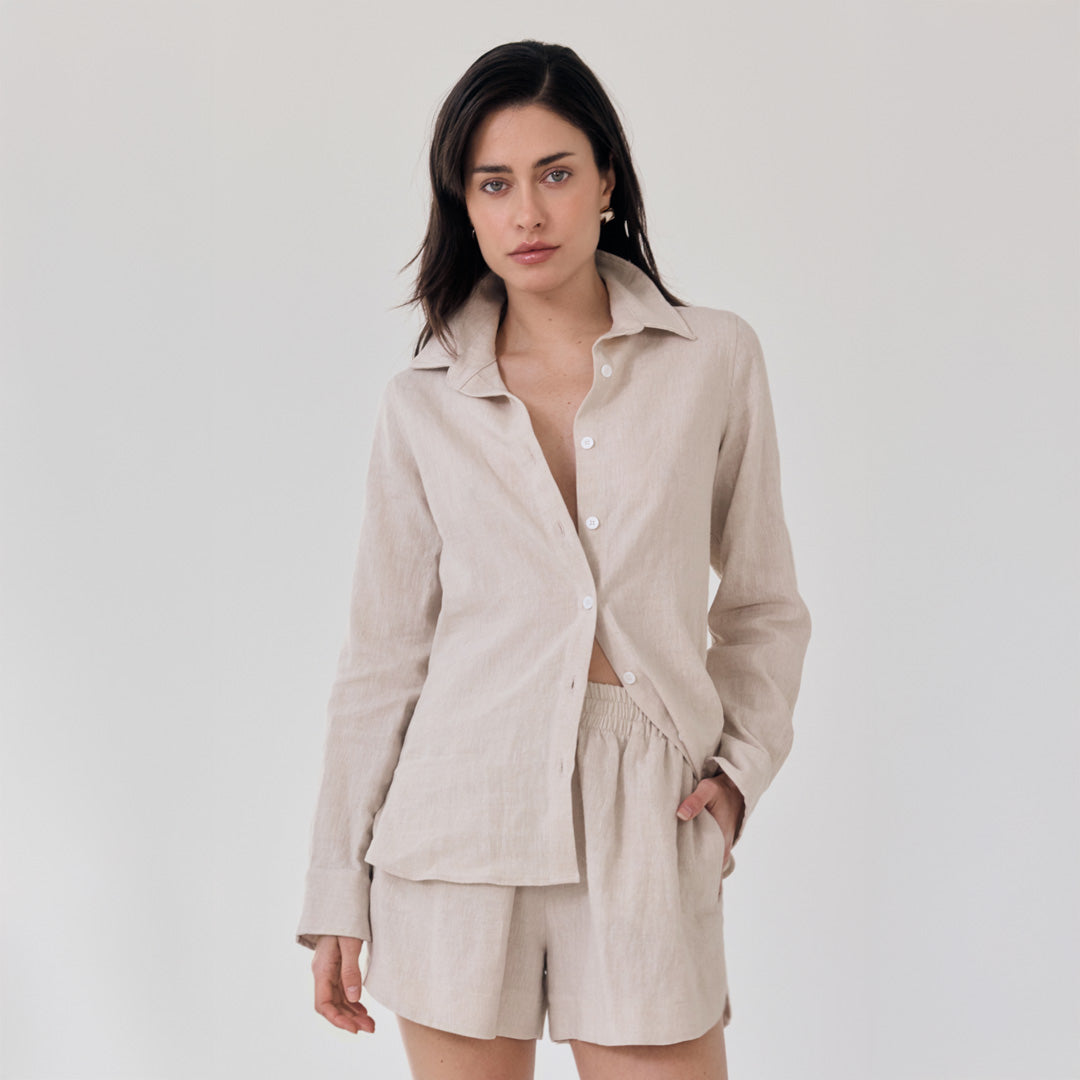 Woman wearing a beige linen outfit on a plain background