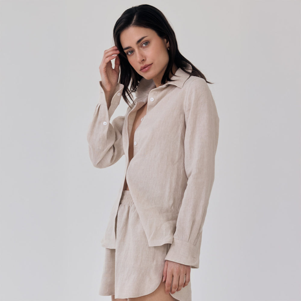 Woman wearing a beige shirt and shorts against a plain background