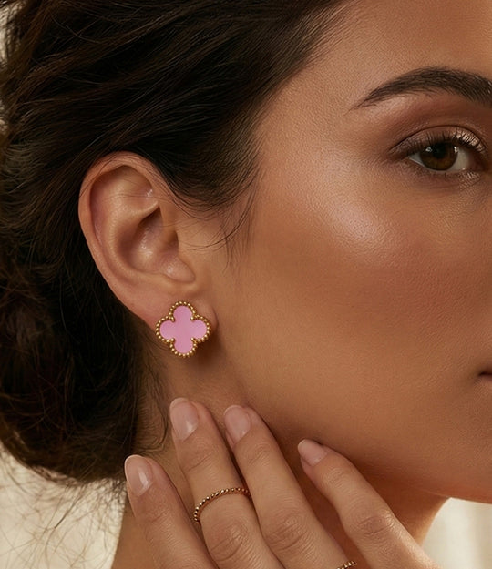 Close-up of a woman wearing pink clover-shaped earrings.