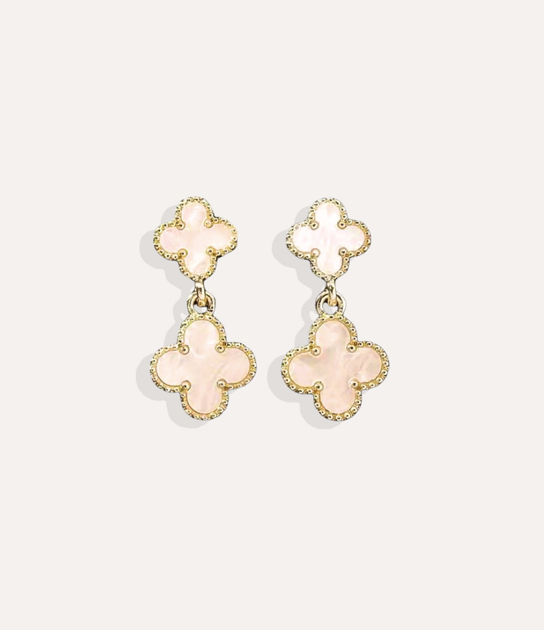 Close up of the white Clover Drop Stud earrings in gold, showcasing the double clover design and dangling detail.