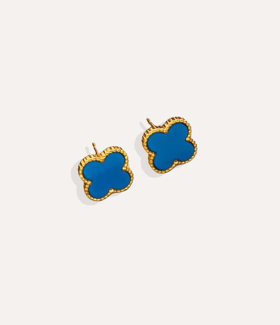 Product shot of the Clover Stud Earrings in a gold finish displaying the lucky four leaf design in blue and warm metallic tone on a white background.