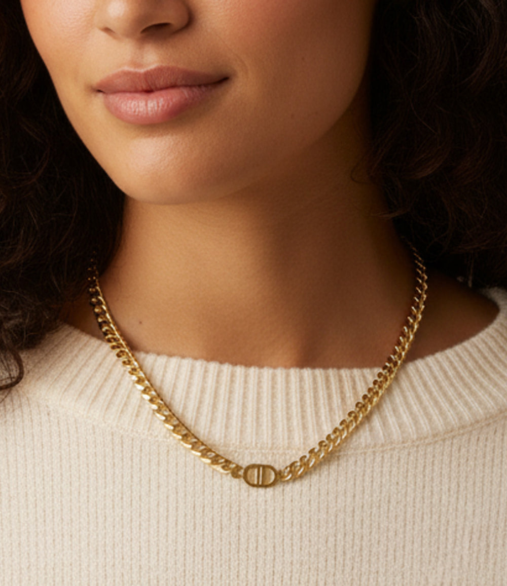 Close-up of a person wearing a gold chain necklace against a neutral background