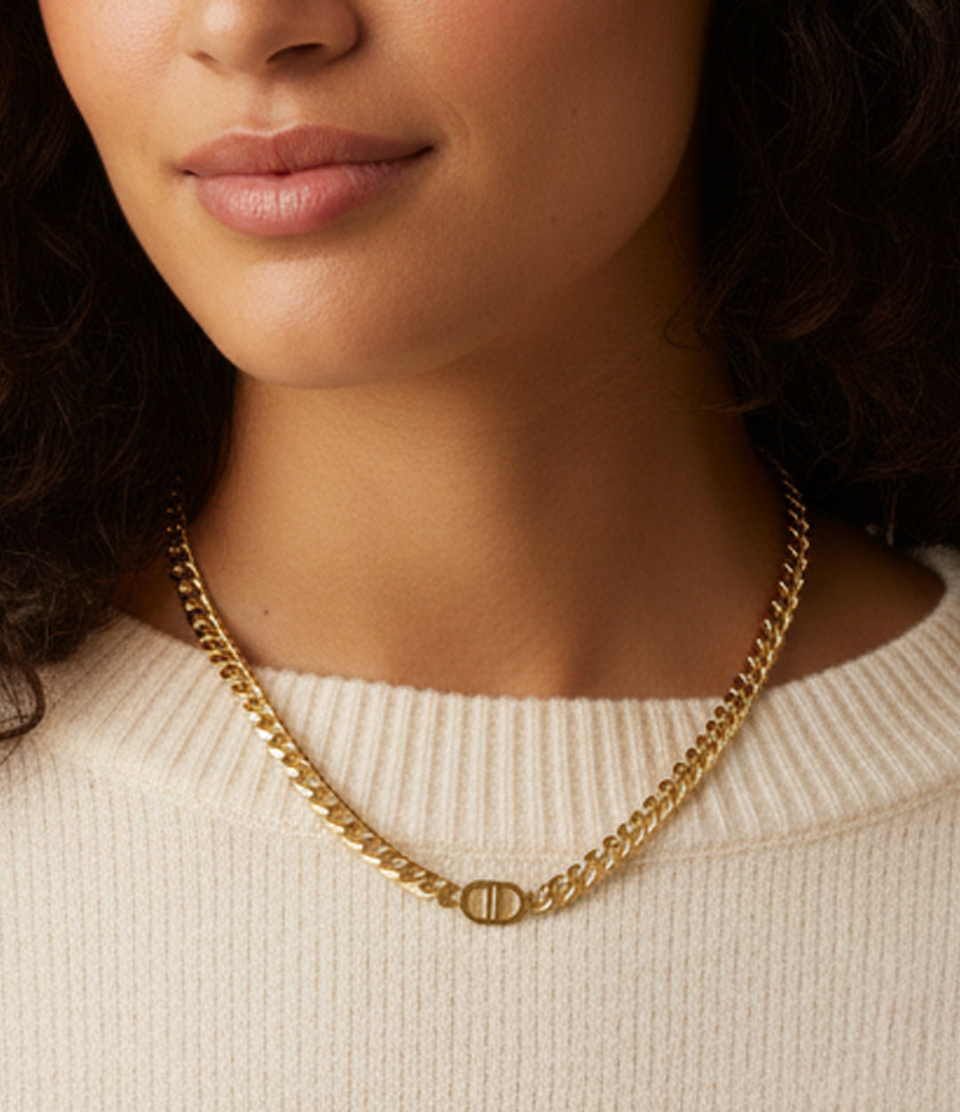 Close-up of a person wearing a gold chain necklace against a neutral background