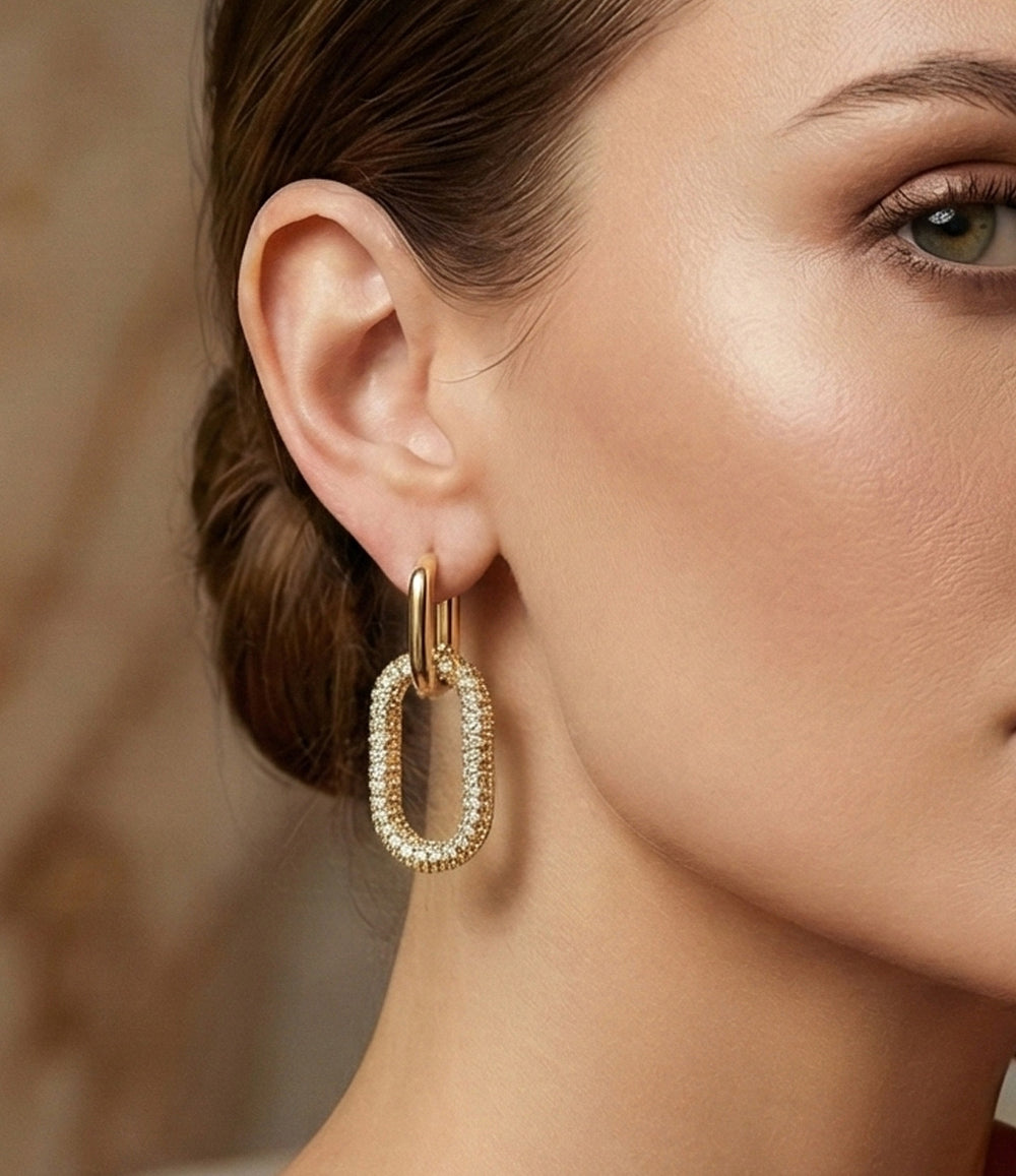 Gold hoop earring worn by a model with a blurred background