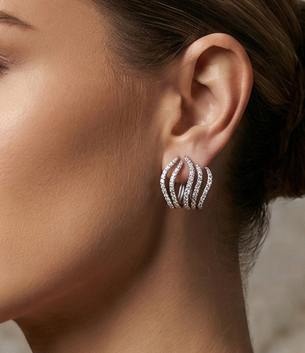 Close-up of an ear wearing a silver hoop earring with clear stones.