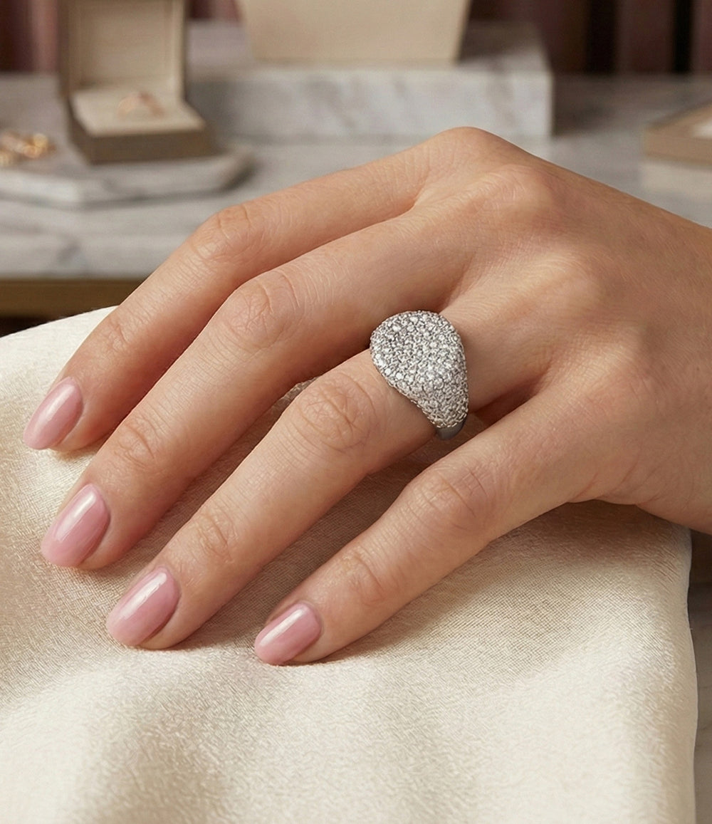 Woman's hand modeling the Diamond Signet Ring on the pinky finger, showcasing the bold flat-top design and luxurious diamond sparkle against a neutral background.