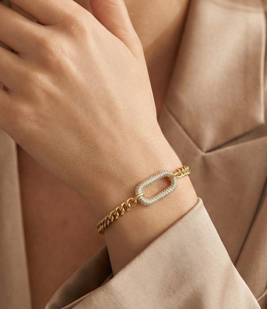 Gold bracelet with a unique clasp worn on a wrist against a beige background