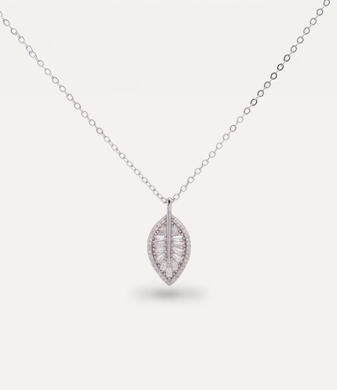Silver leaf-shaped pendant with sparkling diamonds on a chain against a white background
