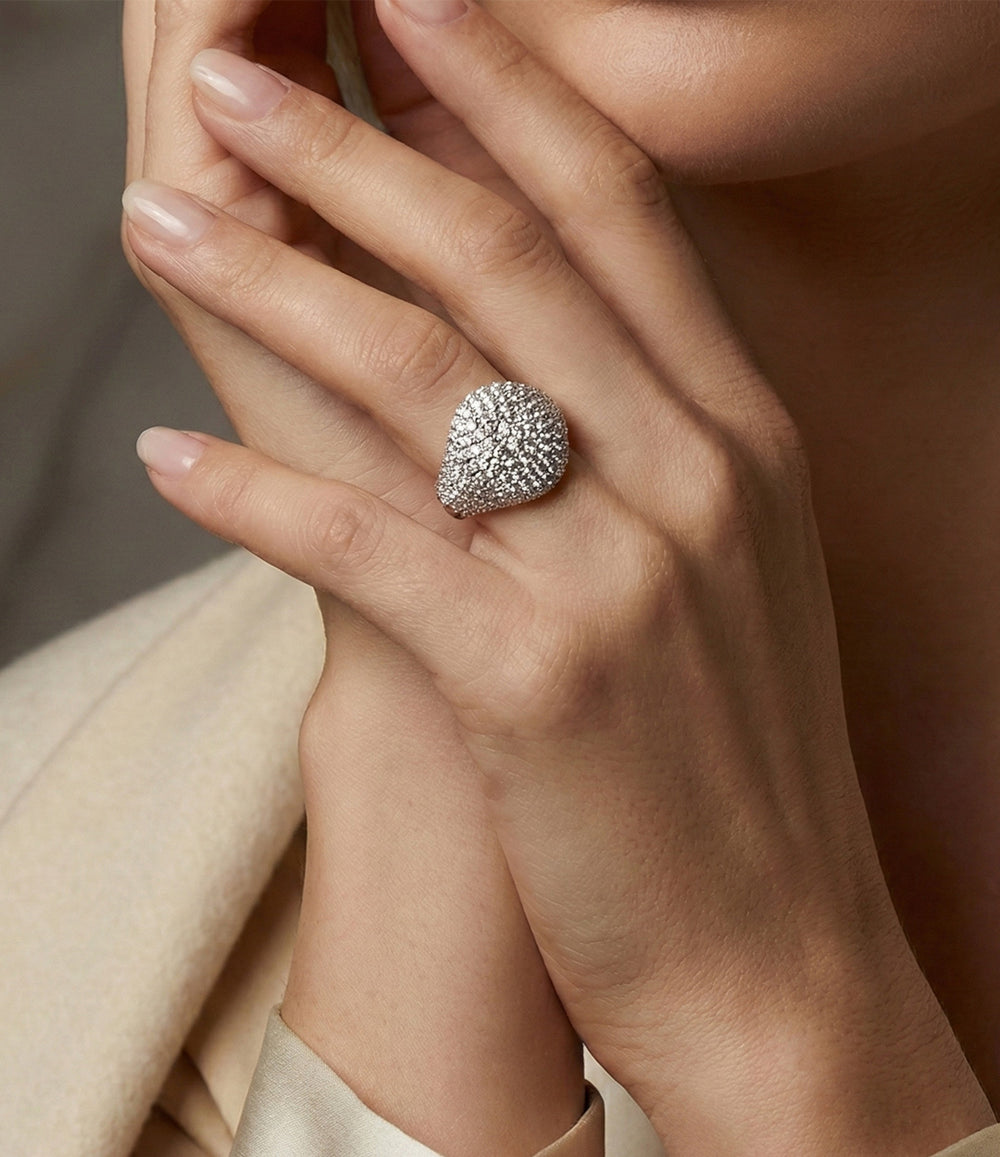 Woman's hand modeling the Diamond Signet Ring on the pinky finger, showcasing the bold flat-top design and luxurious diamond sparkle against a neutral background.