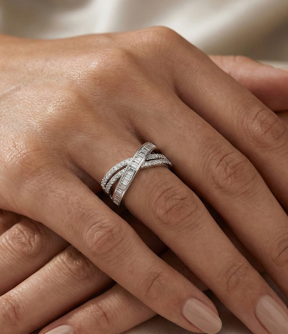 Woman's hand modeling the Diamond Twist Ring on the middle finger, showcasing the modern crisscross X design and diamond accents against a neutral background.