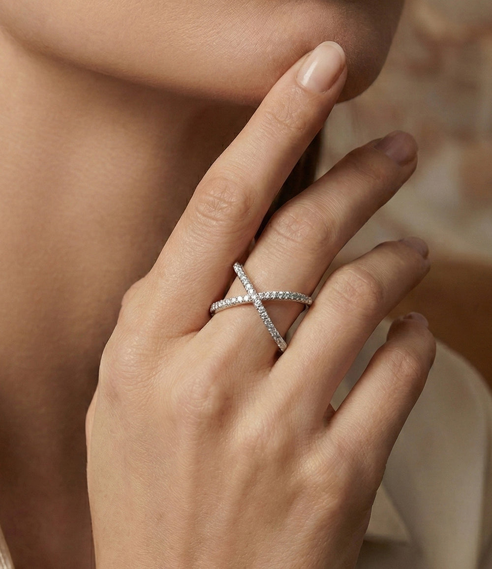 Woman's hand modeling the Diamond X Ring on the ring finger, showcasing the dainty criss-cross design and subtle diamond sparkle.