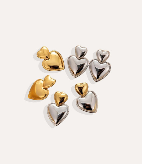 Heart-shaped earrings in gold and silver on a light gray background