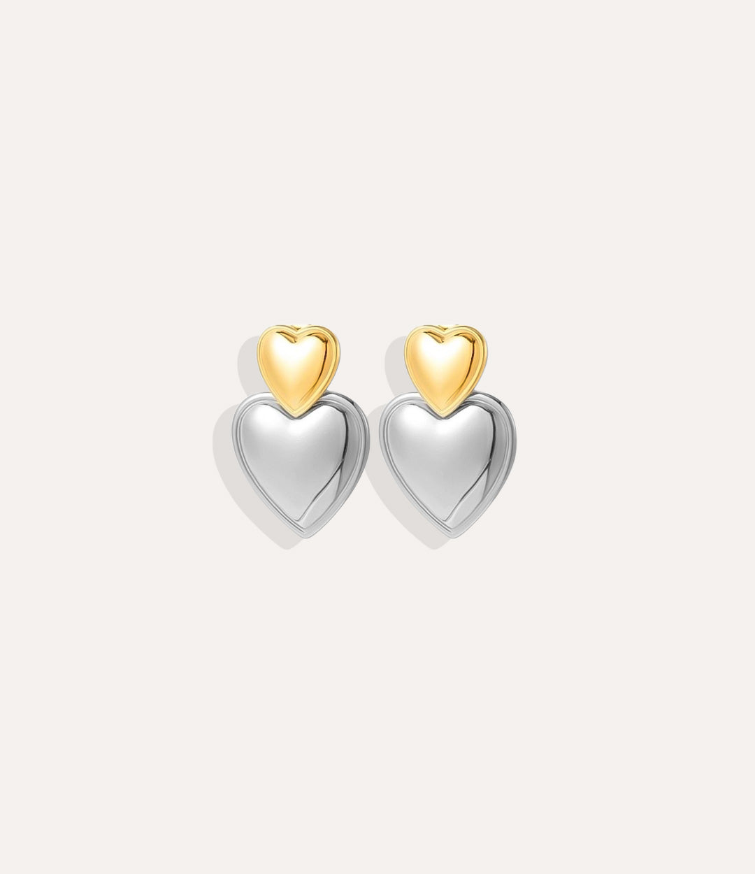 Heart-shaped earrings with gold and silver finishes on a white background
