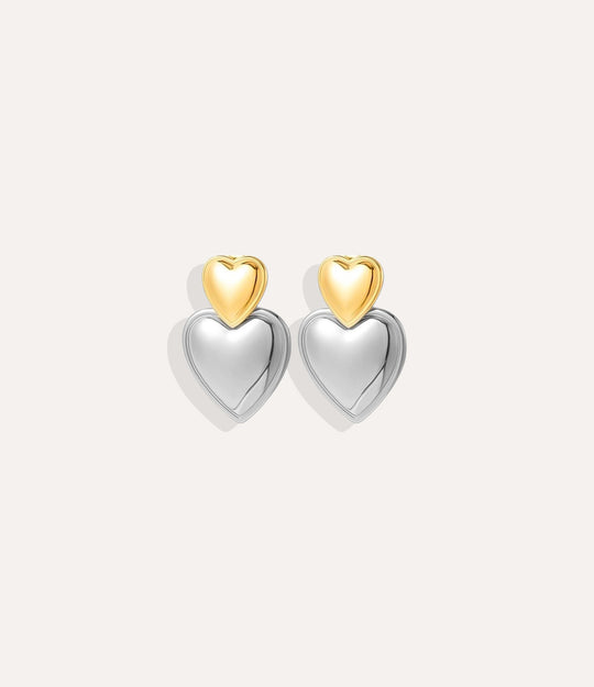 Heart-shaped earrings with gold and silver finishes on a white background