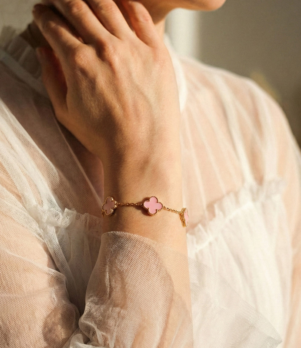 Model wearing the Double Sided Clover Bracelet in pink, showcasing the classic clover charm and elegant gold bracelet design.