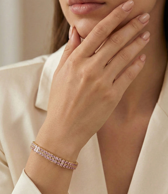Close-up of a hand wearing a rose gold bracelet with a neutral background