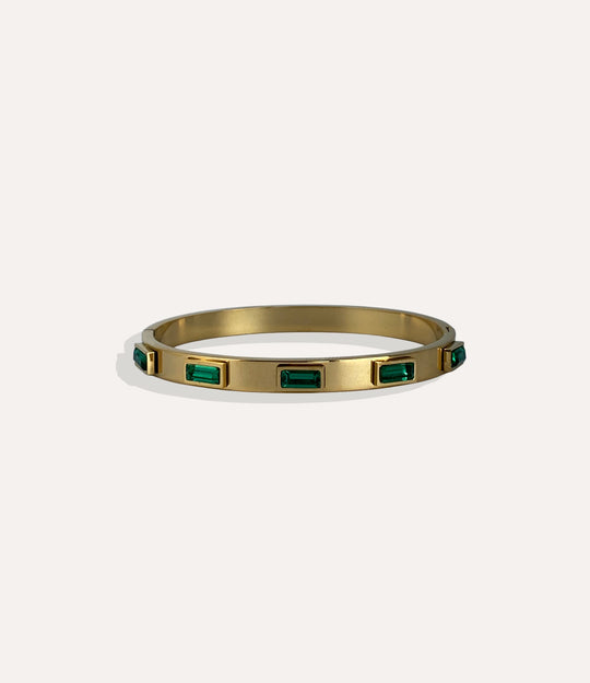 Gold bracelet with emerald green stones on a white background