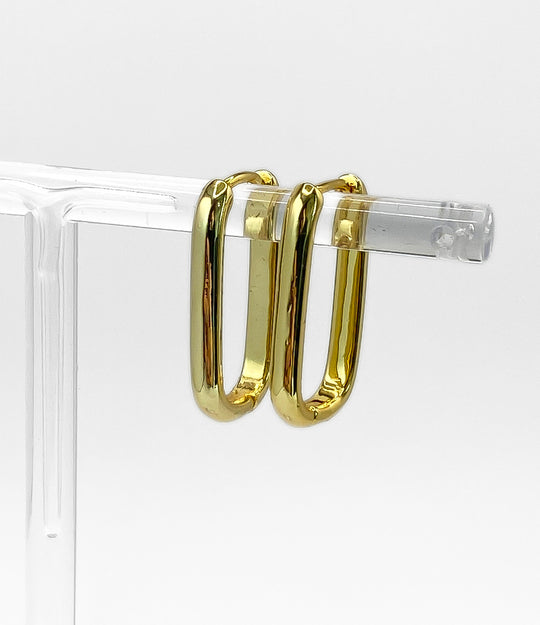 Gold hoop earrings on a clear stand against a white background