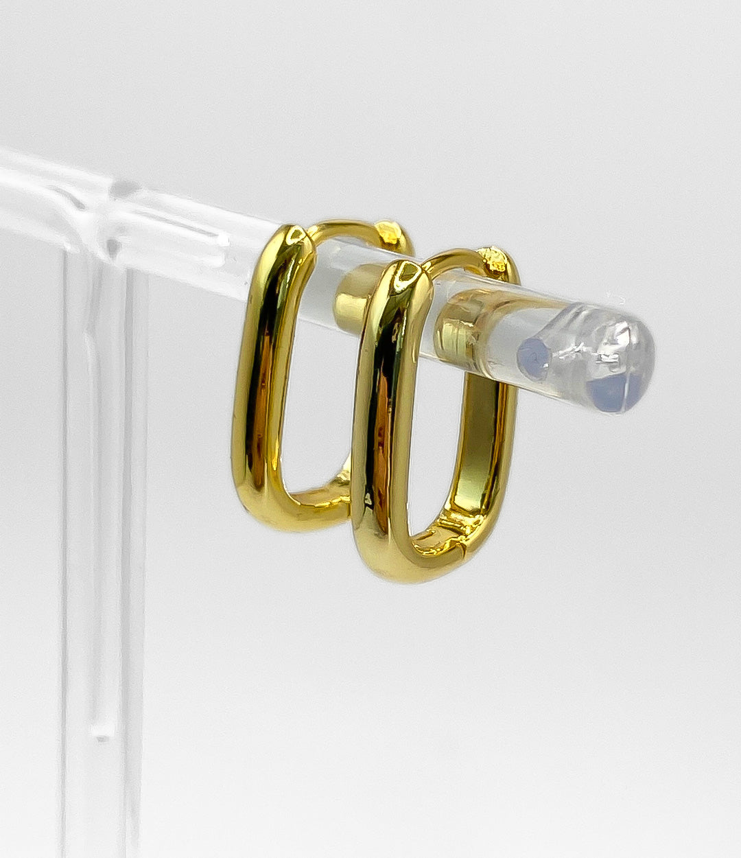 Gold hoop earrings on a clear stand against a white background