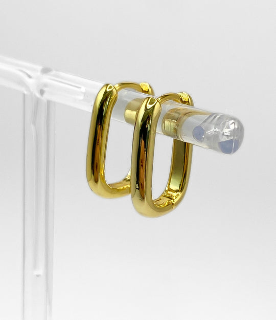 Gold hoop earrings on a clear stand against a white background